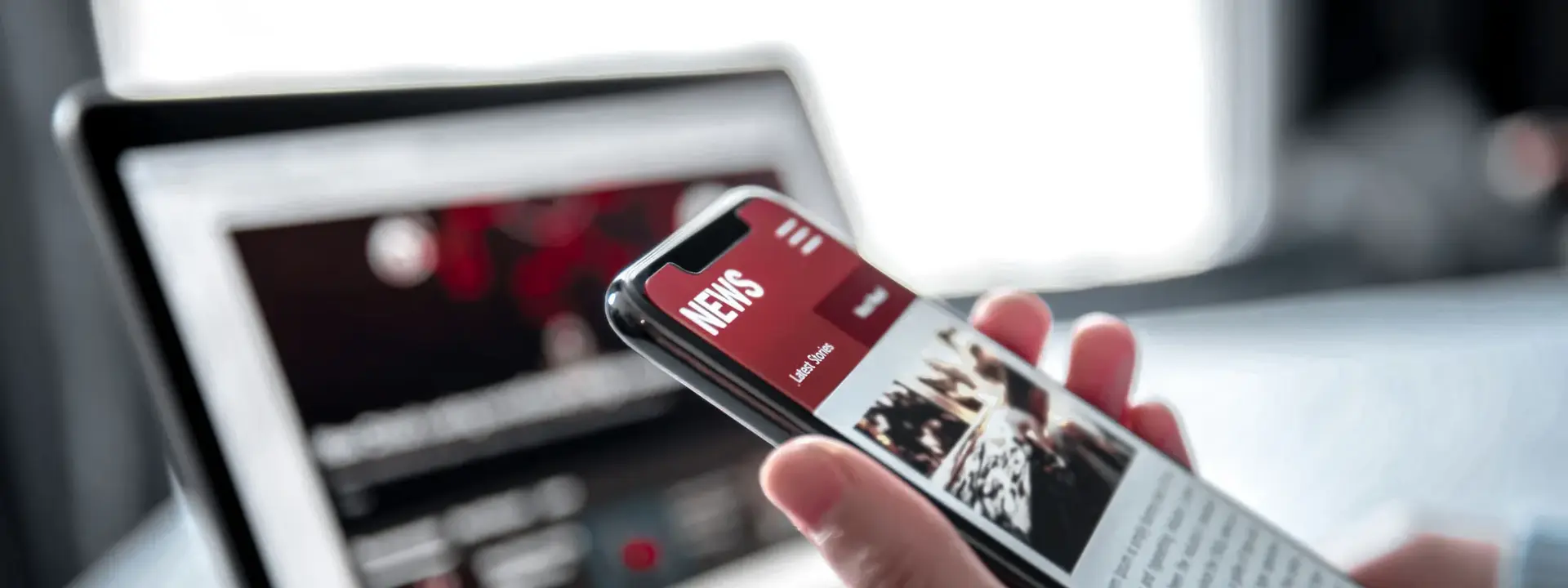 A smartphone with a laptop in the background