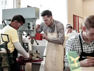 一群人在车间的一台机器上工作